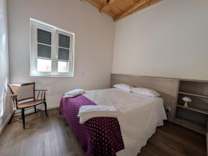 a bedroom with a bed and a chair and two windows at Casas Albano 1 in Caldas da Rainha