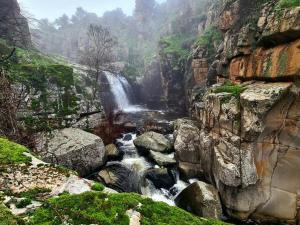a waterfall on the side of a mountain with rocks at Alma de Barro in El Puente del Arzobispo