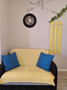 a couch with two blue pillows and a clock on the wall at Sunny Studio Mamaia Nord in Mamaia Sat/Năvodari