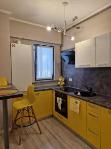 a kitchen with yellow cabinets and a sink and a table at Sunny Studio Mamaia Nord in Mamaia Sat/Năvodari