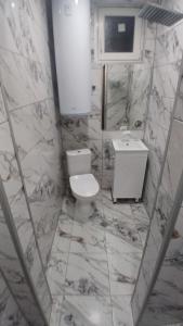 a white bathroom with a toilet and a sink at Апартамент за гости Вамсон in Velingrad +8 photos