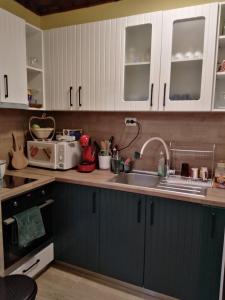 a kitchen with white cabinets and a sink and a microwave at Апартамент за гости Вамсон in Velingrad