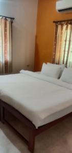 a bed with white sheets and pillows in a room at Flobestian's Seafront Villa in Candolim