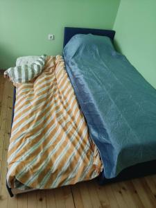 an unmade bed in a bedroom with a wooden floor at Апартамент за гости Вамсон in Velingrad