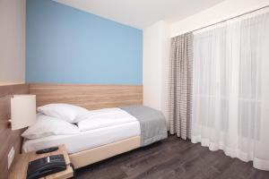 ein weißes Schlafzimmer mit einem Bett und einem Fenster in der Unterkunft Hôtel de Chailly in Montreux