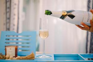 a person pouring a glass of white wine at 2 Bedroom en-suite studios by The Prime Escape in Arusha