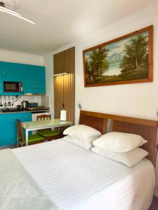 a bedroom with a white bed and a kitchen at Anchor House in Câmara de Lobos
