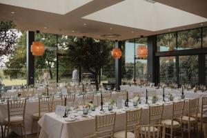 a long table with white tables and chairs in a building at Wildhive Callow Hall in Ashbourne