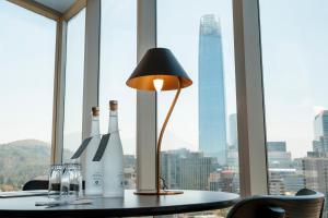 a table with two bottles and a lamp in front of a window at Hotel Terrado Lyon in Santiago
