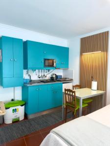 a kitchen with bright blue cabinets and a table at Anchor House in Câmara de Lobos