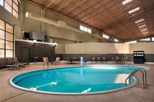 a large swimming pool in a building with tables and chairs at Urbana Hotel Conference Center in Urbana