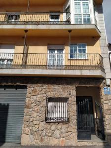 an apartment building with a balcony and windows at La flor del cerezo in Piornal