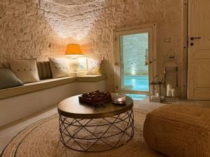 a living room with a table and a window at Trulli Fichi Luxury Trullo with Private Spa and Saltwater Pool in Santa Lucia