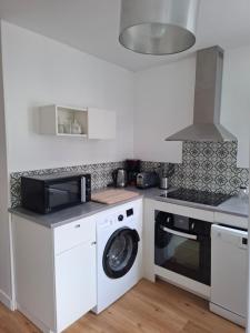 a kitchen with a washing machine and a microwave at Escale cosy à Blois in Blois +2 photos