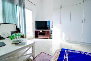 a white living room with a table and a tv at Studio - Private - Abu Dhabi in Abu Dhabi