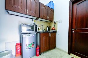 a small kitchen with a refrigerator and wooden cabinets at Studio - Private - Abu Dhabi in Abu Dhabi