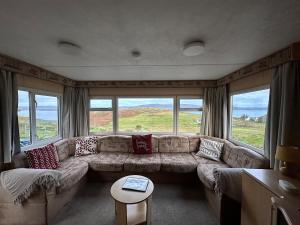 a living room with a large couch and windows at Croft View Caravan Holidays in Dunvegan