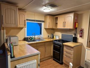 a kitchen with wooden cabinets and a stove top oven at Croft View Caravan Holidays in Dunvegan +11 photos