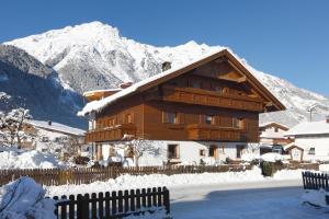 a large wooden building with snow covered mountains in the background at Haus Stefan in Längenfeld