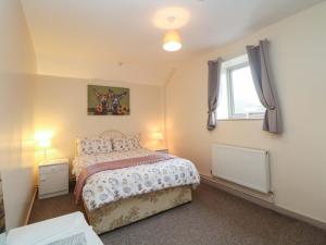 a bedroom with a bed and a window at Ford Coach House Cottage in Leek