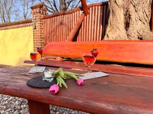 a wooden bench with two glasses and flowers on it at L&L Skaters Home in Langenlipsdorf