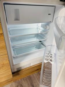 an empty refrigerator with its door open in a kitchen at Too Apartment Lipno in Černá v Pošumaví