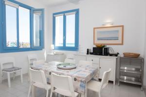 a dining room with a table and chairs and windows at Casa Blu sul mare e centralissima in San Vito lo Capo
