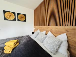 a bedroom with a bed with a wooden headboard and pillows at Too Apartment Lipno in Černá v Pošumaví