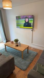 a living room with a table and a tv on the wall at Two-bedroom house with a workspace in Basildon in Nevendon