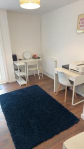 a living room with a table and a blue rug at Two-bedroom house with a workspace in Basildon in Nevendon +8 photos