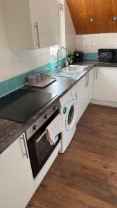 a kitchen with a sink and a washing machine at Two-bedroom house with a workspace in Basildon in Nevendon