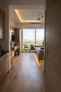 a living room with a large window and a room with a bed at The Rudraya - Suites in Greater Noida