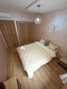 a bedroom with a large bed and a chandelier at Vivienda 01 Appartement moderne au cœur de Mohammedia , Calme et Confort in Mohammedia