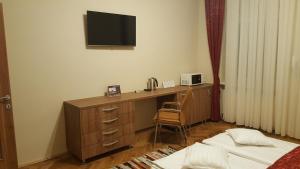 a bedroom with a desk with a television on the wall at Satu Mare Apartments in Satu Mare