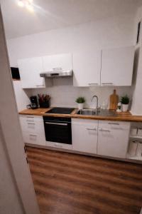 a kitchen with white cabinets and a sink at Appartment Okarben in Karben