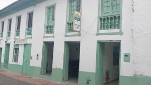 a white building with green doors and windows at Posada La Casona in El Cocuy