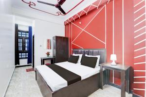 a bedroom with a bed and a red wall at Hotel O Kp Guest House in Bāra Banki