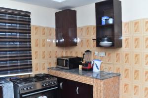 a kitchen with a stove and a microwave at Skye Palace Apartment - Skye Regency 2 Bedroom Apartment in Akure