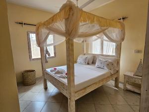 a bedroom with a wooden bed with a canopy at Orange apartment 1 in Watamu