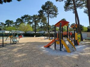a playground with slides and play equipment in a park at Le ptit Galet 462 in La Tremblade
