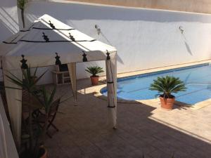 a white umbrella sitting next to a swimming pool at Villa Oasis Ain El Turk in Aïn El Turk +13 photos