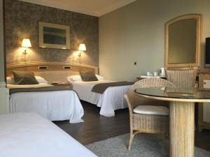 una habitación de hotel con dos camas y una mesa en Las Rocas Playa Hotel, en Castro Urdiales 37 fotos más