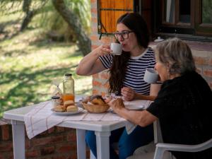 two women sitting at a table with cups of coffee at Sombra de Liebre Casas de Campo en Villa General Belgrano in Villa General Belgrano