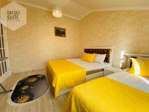 two beds in a small room with yellow sheets at Qafqaz mountain villa in Mekhrably +8 photos