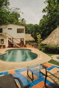 a swimming pool with chairs and a house at Manigua Tayrona Hostel in Santa Marta