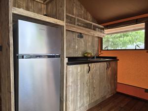 a stainless steel refrigerator in a kitchen with wooden walls at Camping Costa Dorada Tienda Lua in Canet de Mar