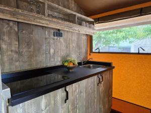 a kitchen with a sink and an orange wall at Camping Costa Dorada Tienda Lua in Canet de Mar