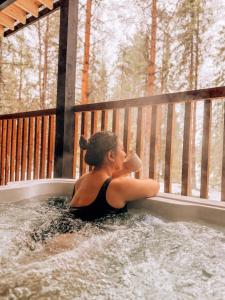 a woman sitting in a hot tub with a drink at NOA VILLAS Aurora Lapland Resort in Takala +57 photos