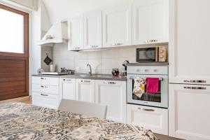 a white kitchen with white cabinets and a microwave at La casetta di pami- Enjoy Apulia in Monopoli