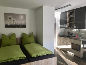 a bedroom with a bed with green pillows and a kitchen at Apartments Reischl in Bergkirchen